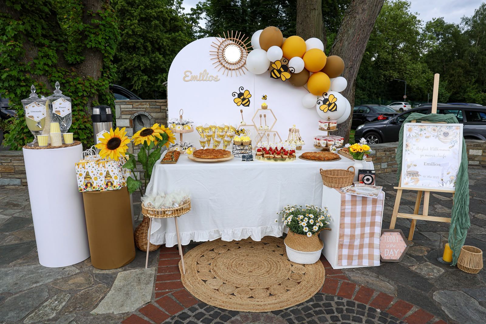 Taufe mit Bienen-Motto: Sweet Table mit Sonnenblumen, honigfarbenen Ballons und personalisierter Rückwand für Emilios